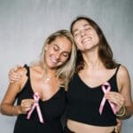 Fundraising w szkole krok po kroku: kampania, sponsorzy, darowizny i rozliczenia Dwie uśmiechnięte kobiety trzymające różowe wstążki fundraising szkolny