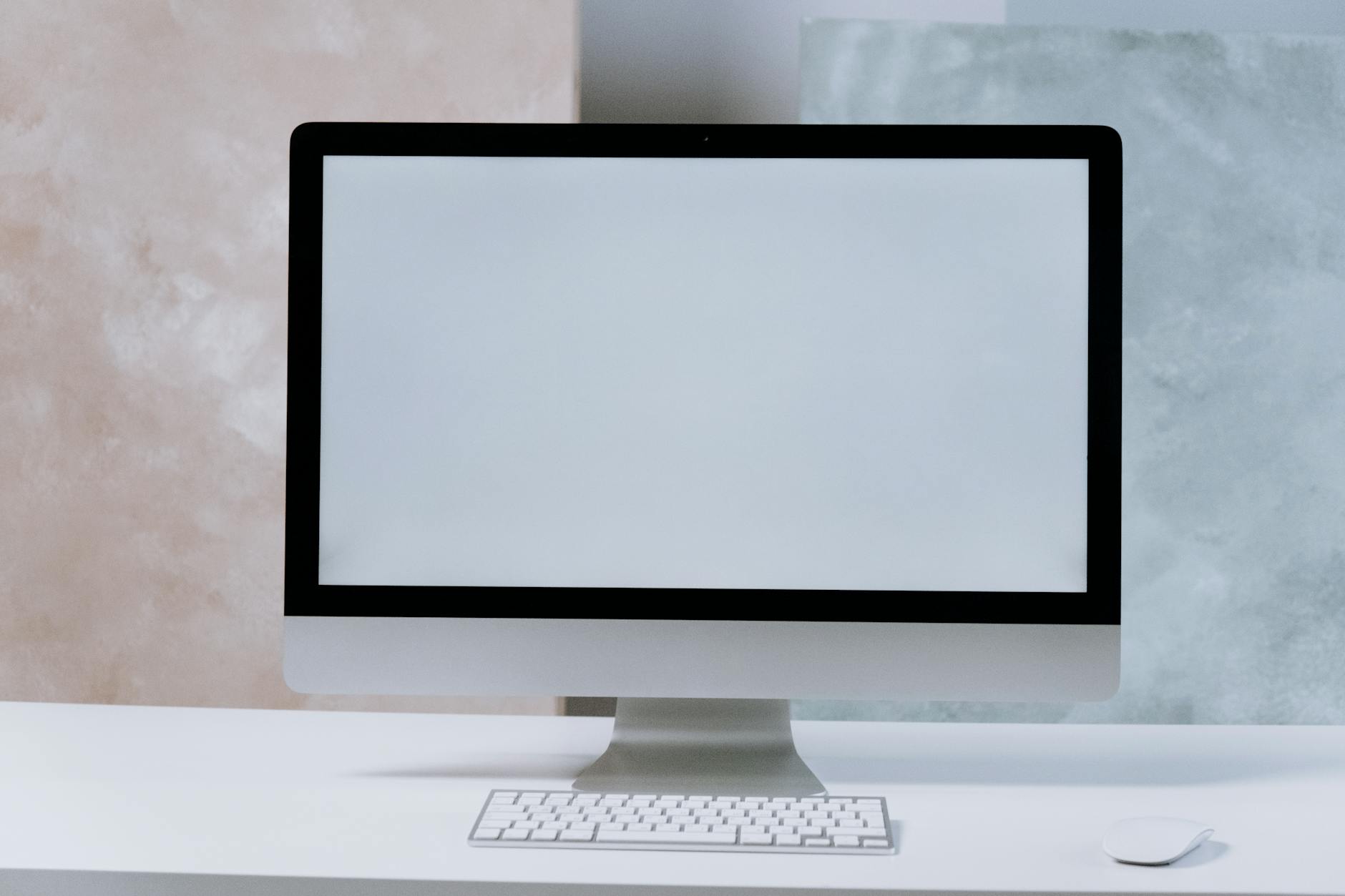 iMac na białym minimalistycznym biurku w nowoczesnej pracowni