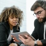 Dwóch specjalistów analizuje dane na tablecie w nowoczesnym biurze