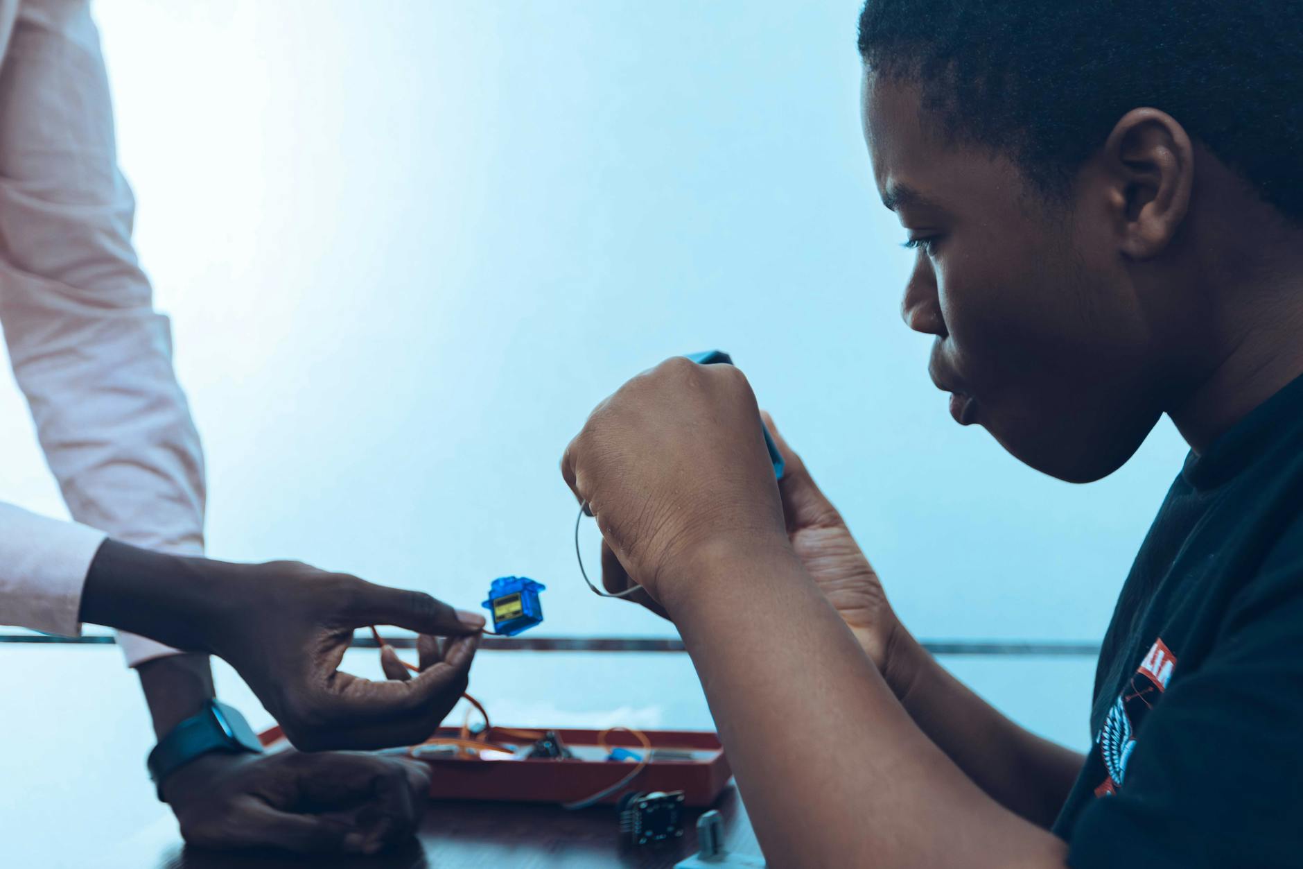 Programowanie w parach w szkole: technika, która poprawia wyniki i współpracę Dwóch uczniów łączy podzespoły elektroniczne na lekcji programowania