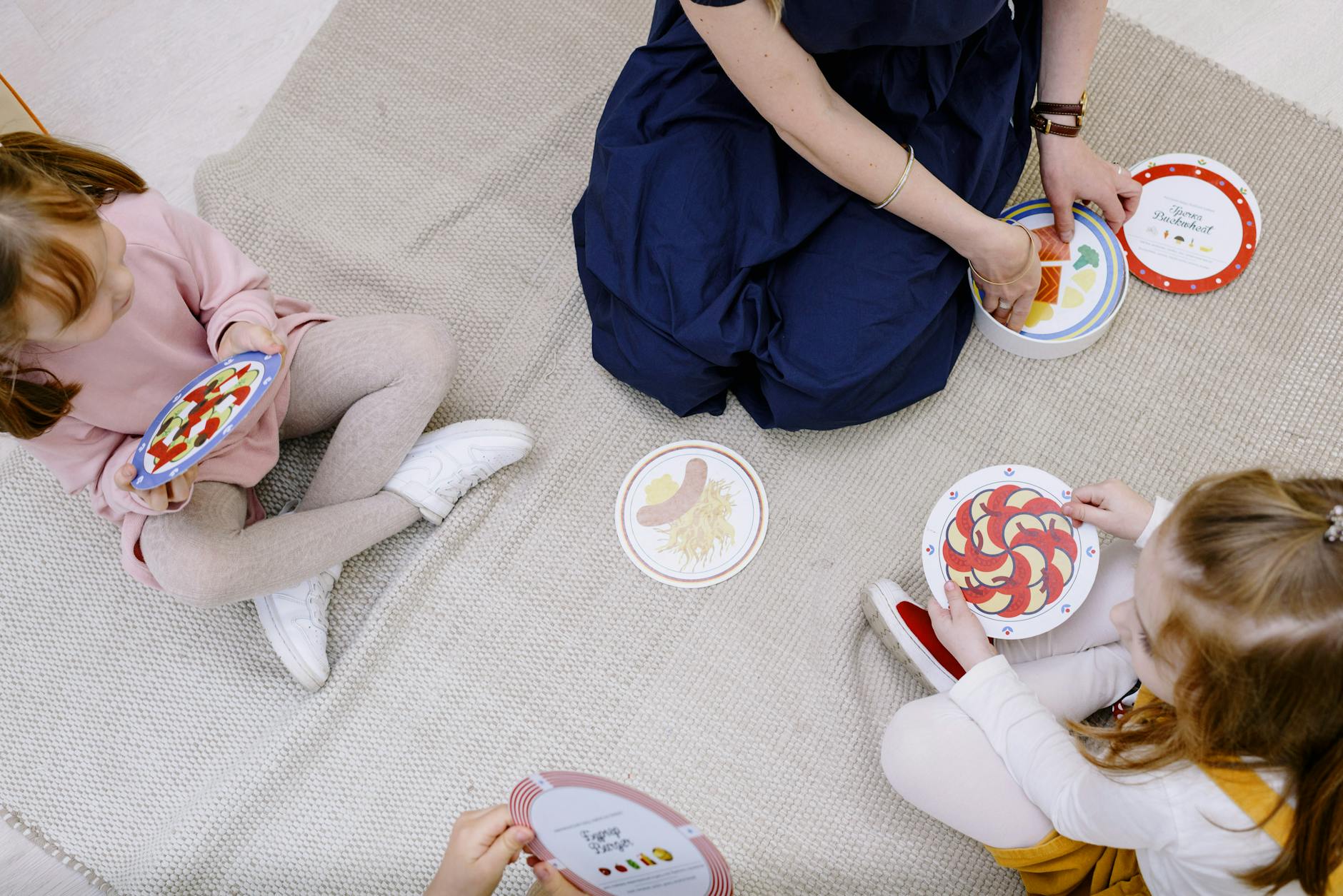 Nauczyciel gra w karty z trojgiem dzieci, rozwijając ich kompetencje społeczne