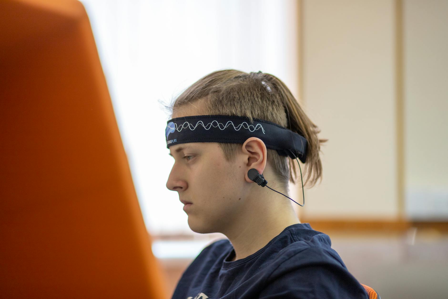 Młody mężczyzna w opasce EEG koncentrujący się na nauce przy biurku