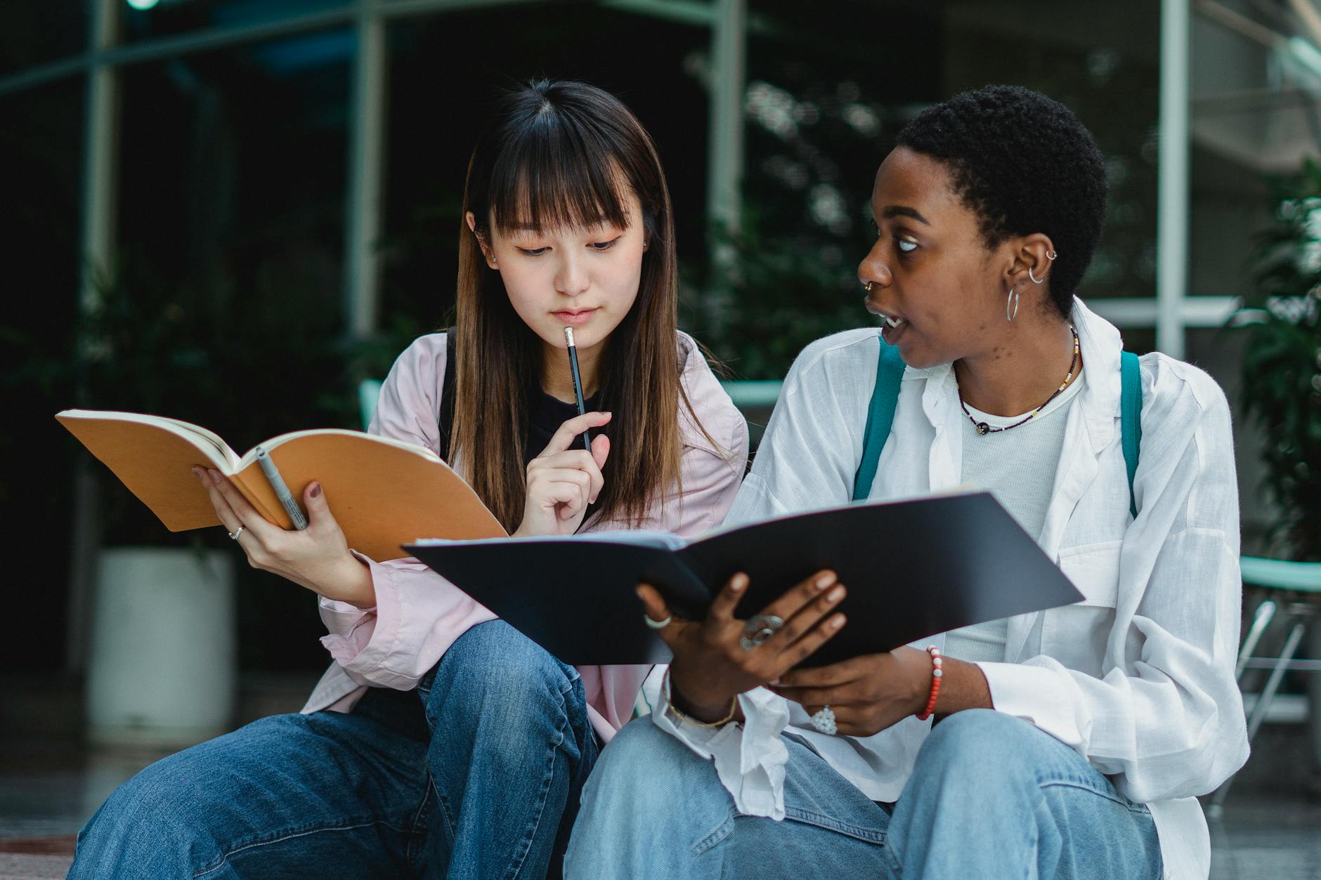 Dwie studentki rozmawiają i uczą się razem na ulicy z zeszytem