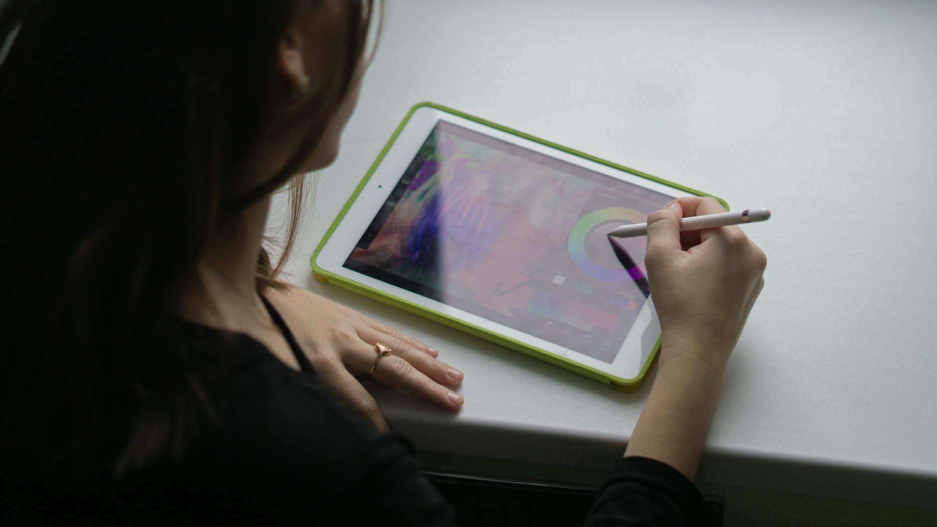 Kobieta rysuje cyfrowo na tablecie w pracowni plastycznej