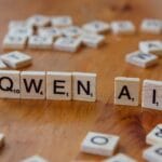 Kafelki jak Scrabble układające napis Qwen AI na drewnianym blacie