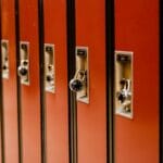 Rząd brązowych szkolnych szafek zamykanych na kłódki w korytarzu