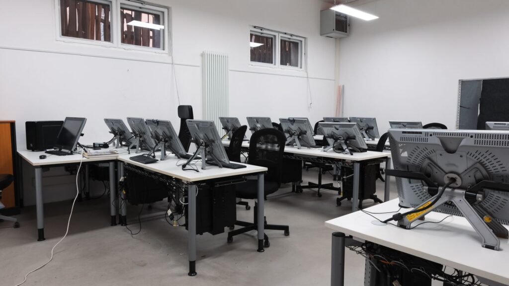 Pusta pracownia komputerowa z nowoczesnymi monitorami na stanowiskach