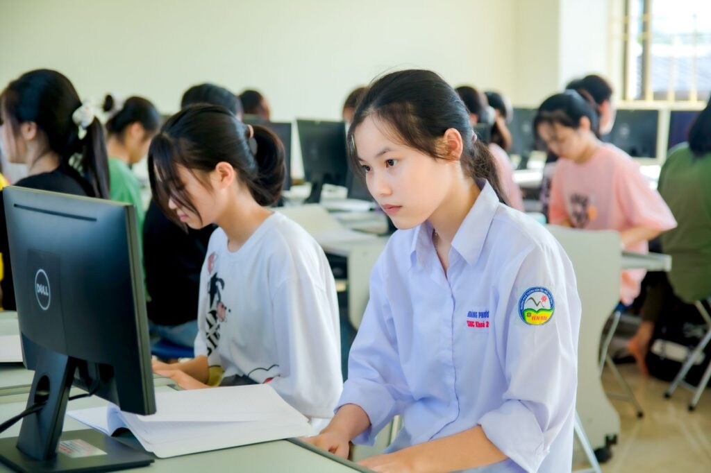 Studenci pracujący przy komputerach w nowoczesnej sali zajęciowej